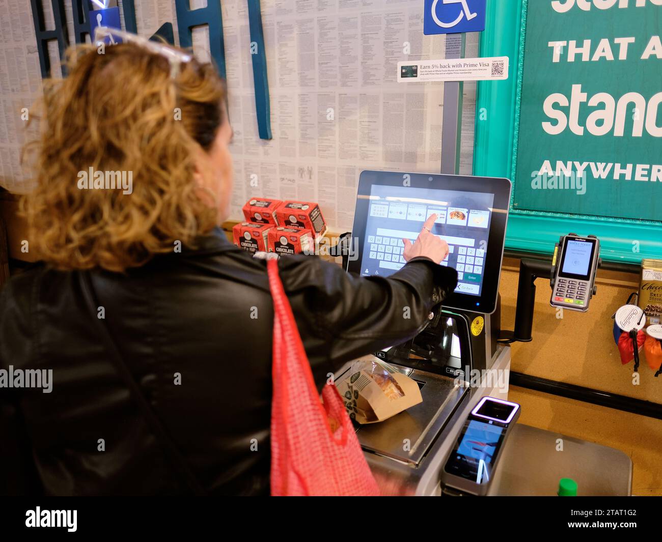Frau, die an einer automatisierten Selbstkasse in einem Whole Foods-Supermarkt in San Francisco, Kalifornien, auscheckt; über das Tastenfeld. Stockfoto