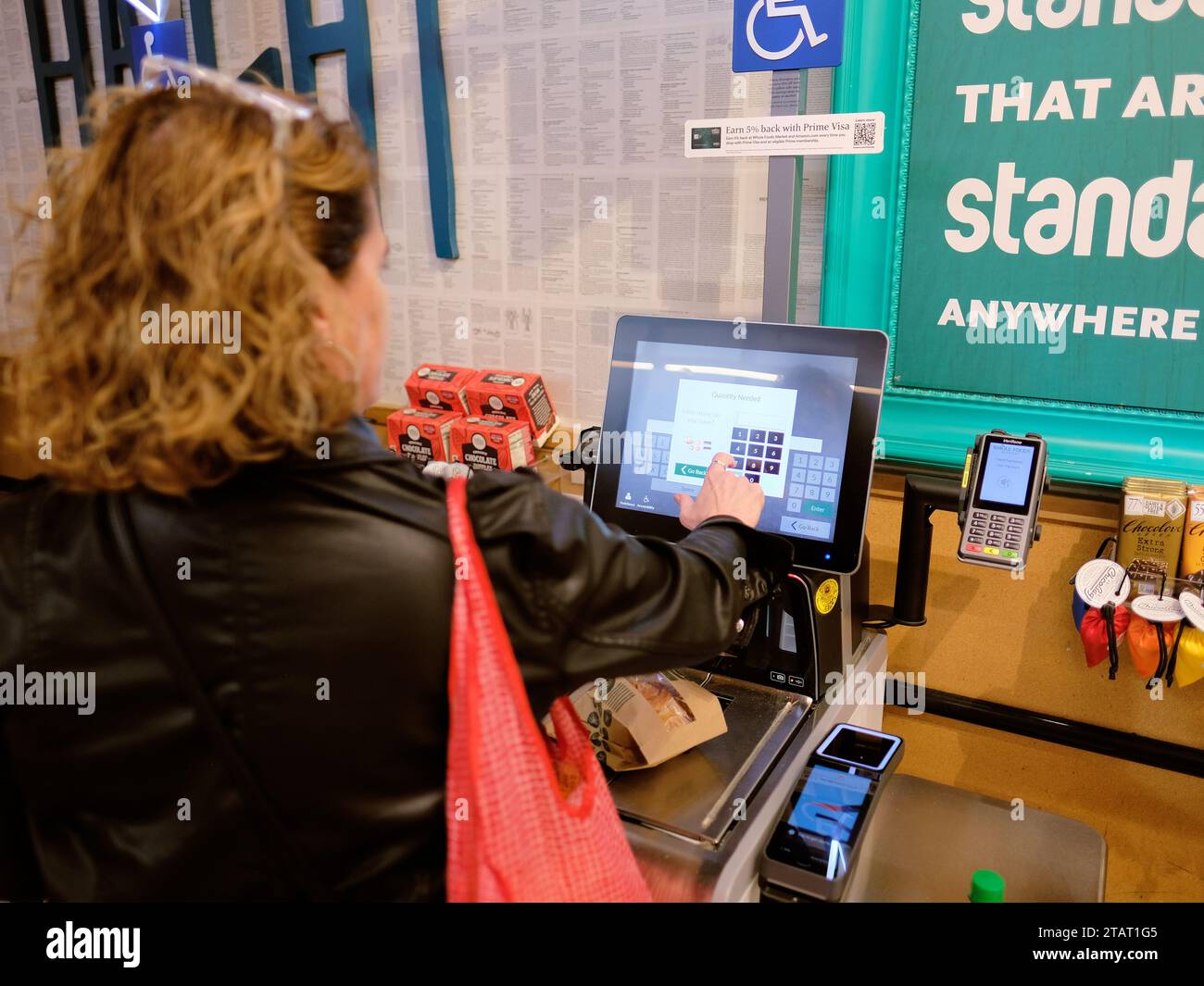 Frau, die an einer automatisierten Selbstkasse in einem Whole Foods-Supermarkt in San Francisco, Kalifornien, auscheckt; über das Tastenfeld. Stockfoto