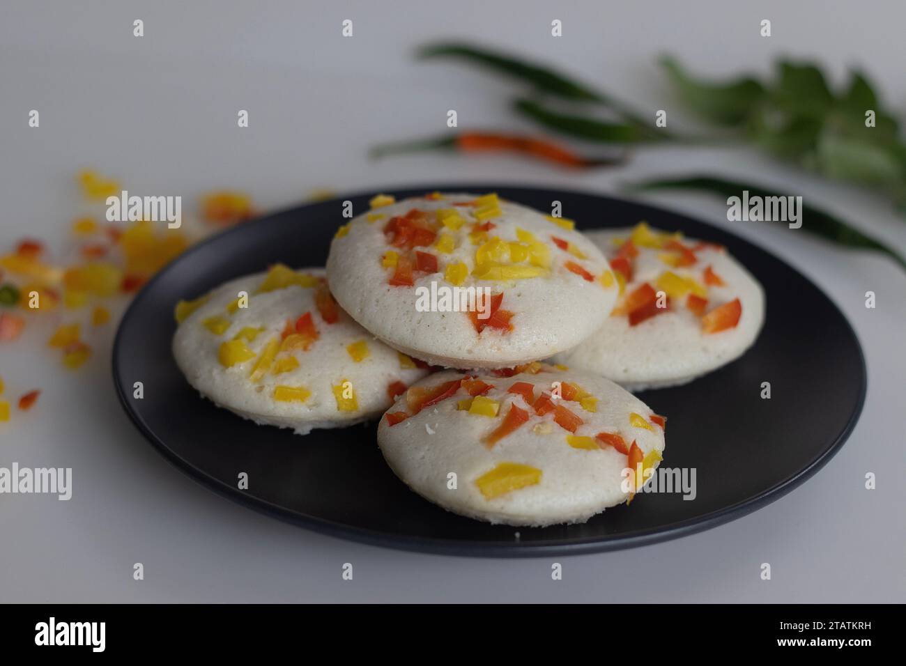 Herzhafte Paprika. Ein farbenfrohes und appetitliches südindisches Frühstück. Gedämpfter herzhafter Reiskuchen mit fermentiertem Teig aus schwarzen Linsen und Ri Stockfoto