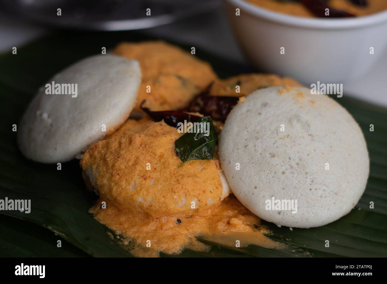 Mit Kokos-Chutney. Gedämpfter herzhafter Reiskuchen mit einem Teig fermentierter schwarzer Linsen und Reis. Serviert auf einem Bananenblatt entlang wi Stockfoto