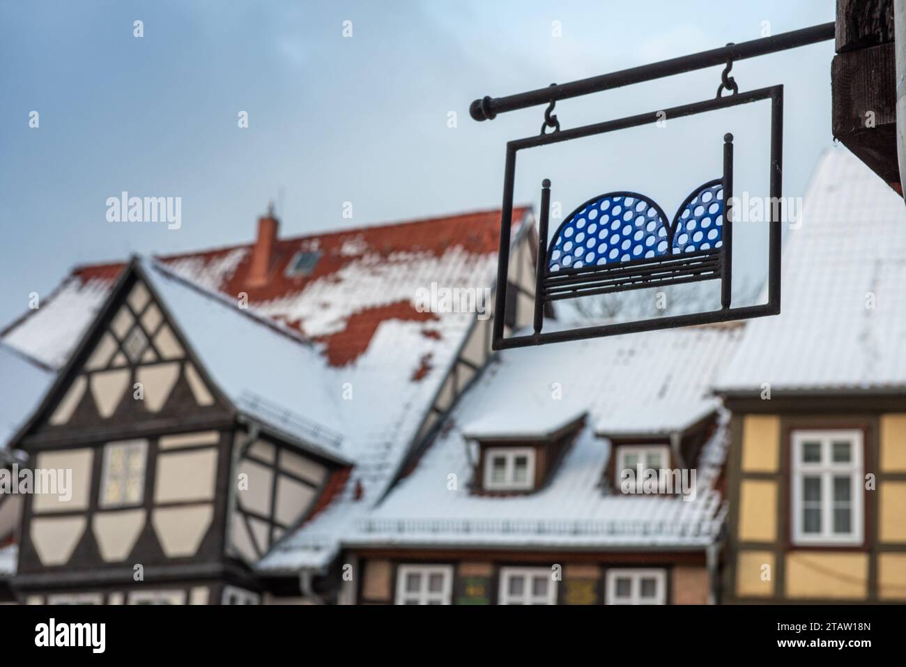 Schild (Symbol für Übernachtung) auf Ferienwohnung vor Fachwerkhäusern mit schneebedeckten Dächern Stockfoto