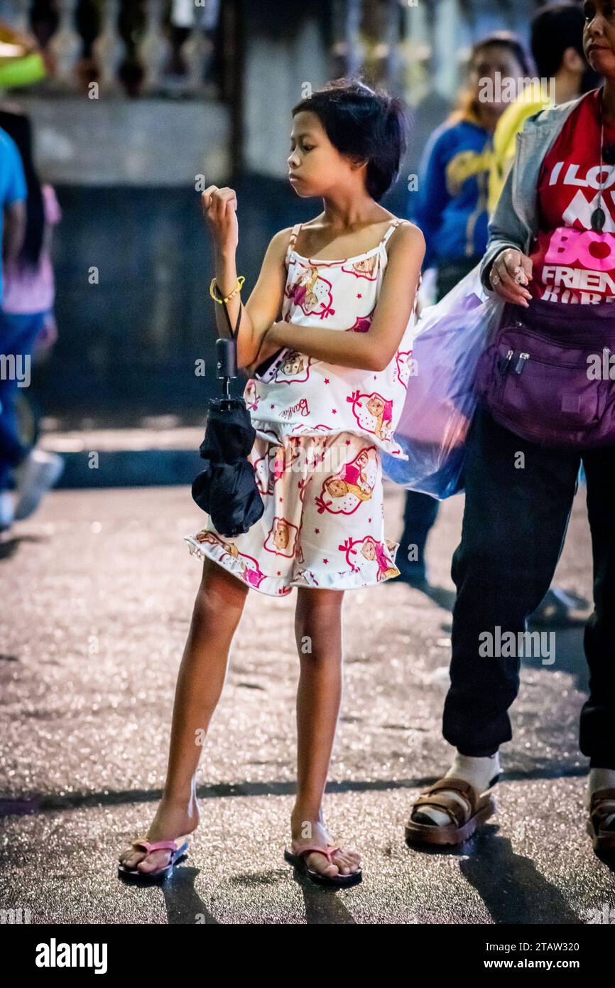 Ein hübsches, junges philippinisches Mädchen wartet auf ihre Familie vor der Kirche Santo Nino de Tondo in Manila auf den Philippinen. Stockfoto