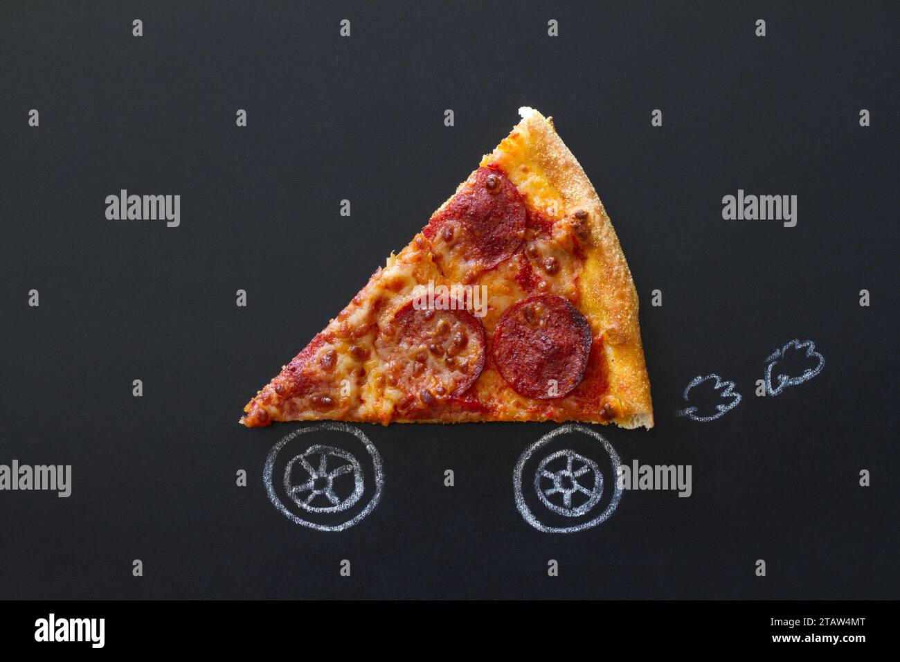 Ein Stück frischer Peperoni-Pizza mit Fahrzeugrädern auf Tafel, Konzept für die Lieferung von Speisen, kreative Idee Stockfoto