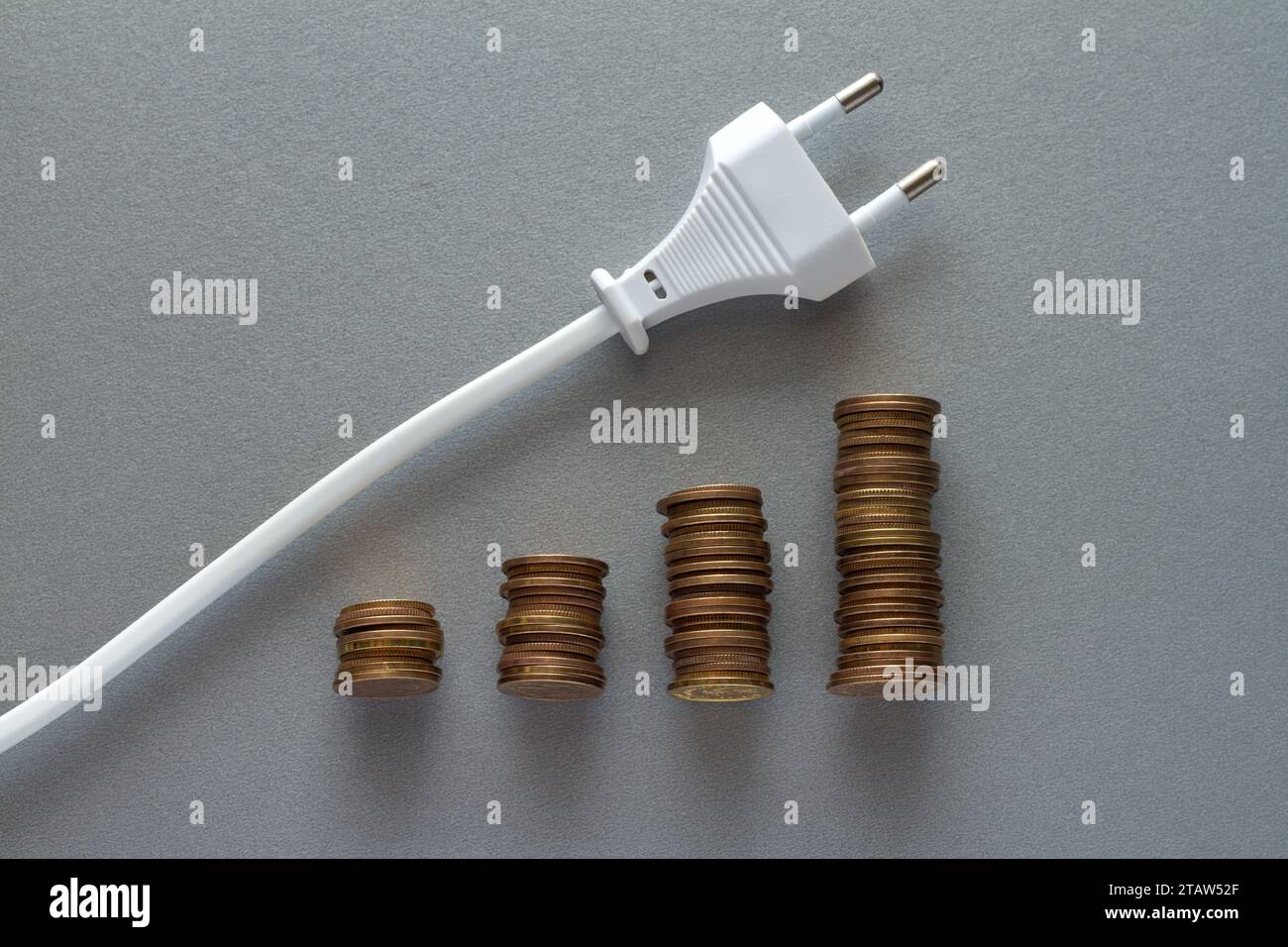 Steigende Energiekosten, Münzstapel mit Kabel mit Stecker nach oben, Strompreistabelle Stockfoto