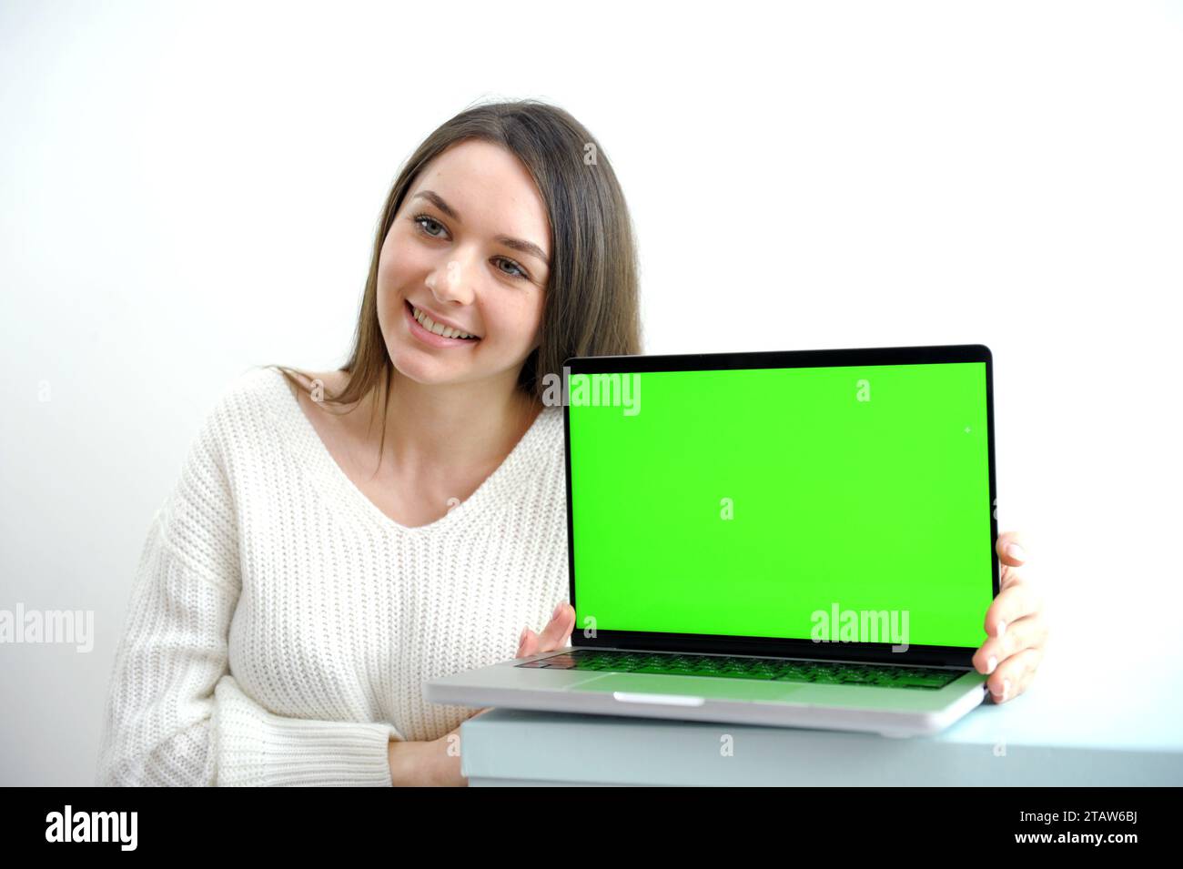 Die junge Frau benutzt den Chroma-Schlüssel auf dem Laptop, während sie in der Wohnung sitzt. Hochwertige Fotos Stockfoto