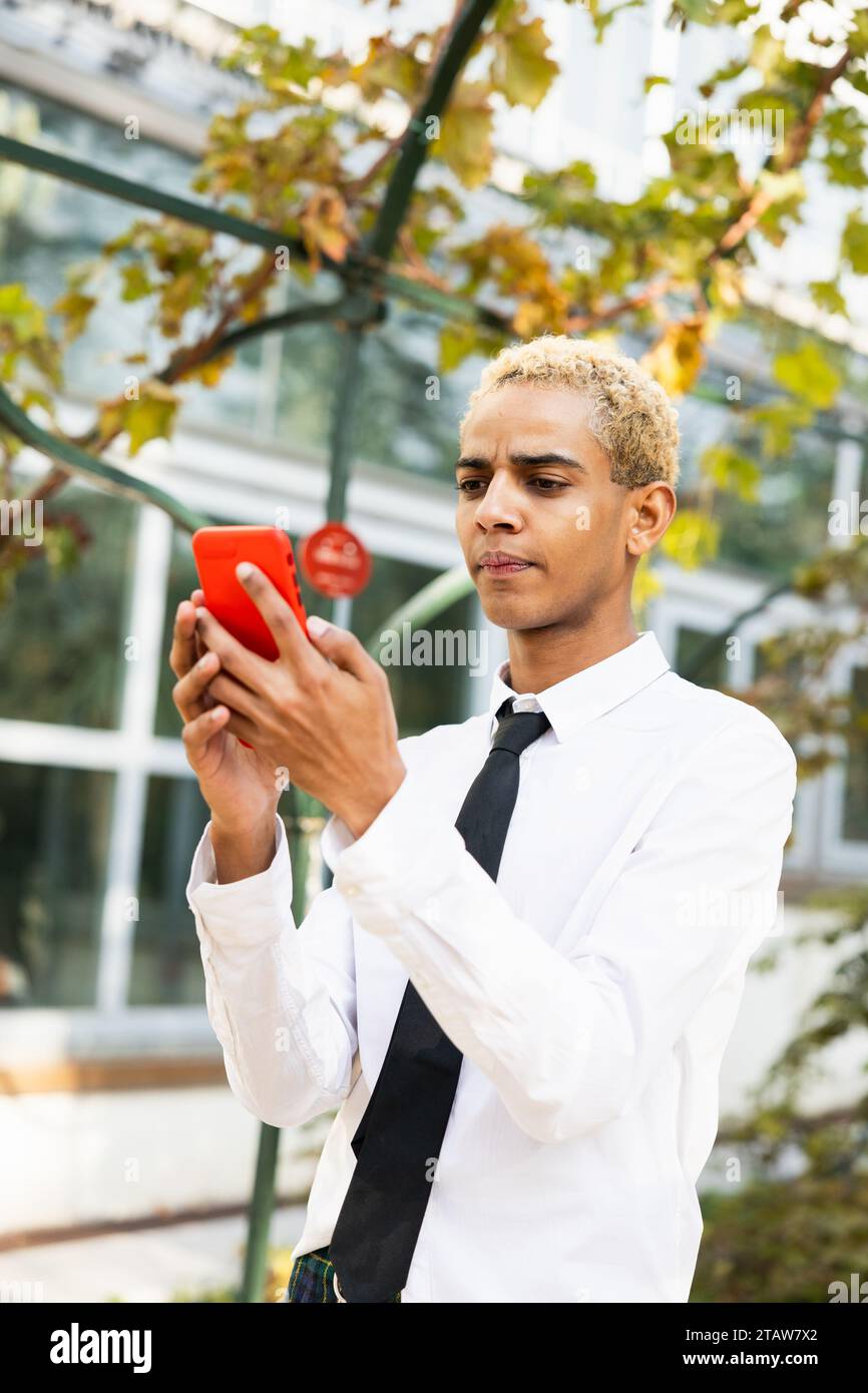 Wunderschöner junger Mann mit überraschtem Ausdruck mit der Nachricht auf dem Handy Stockfoto