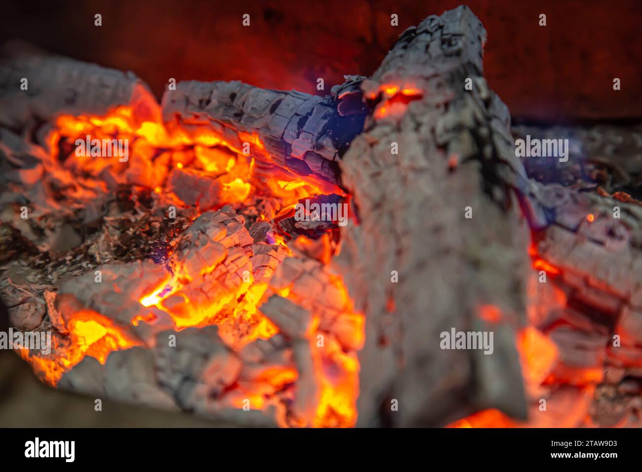 Brennholz schwelt mit einer roten Flamme im Kamin Stockfoto