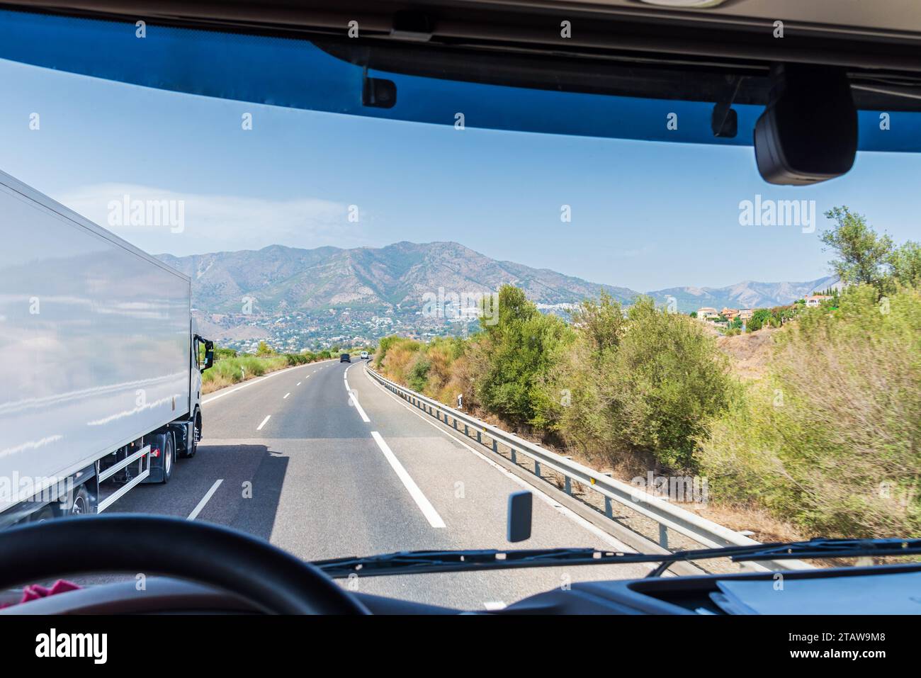 Blick vom Fahrersitz eines Lkws auf einen anderen Kühlwagen, der auf einer Autobahn überholt. Stockfoto