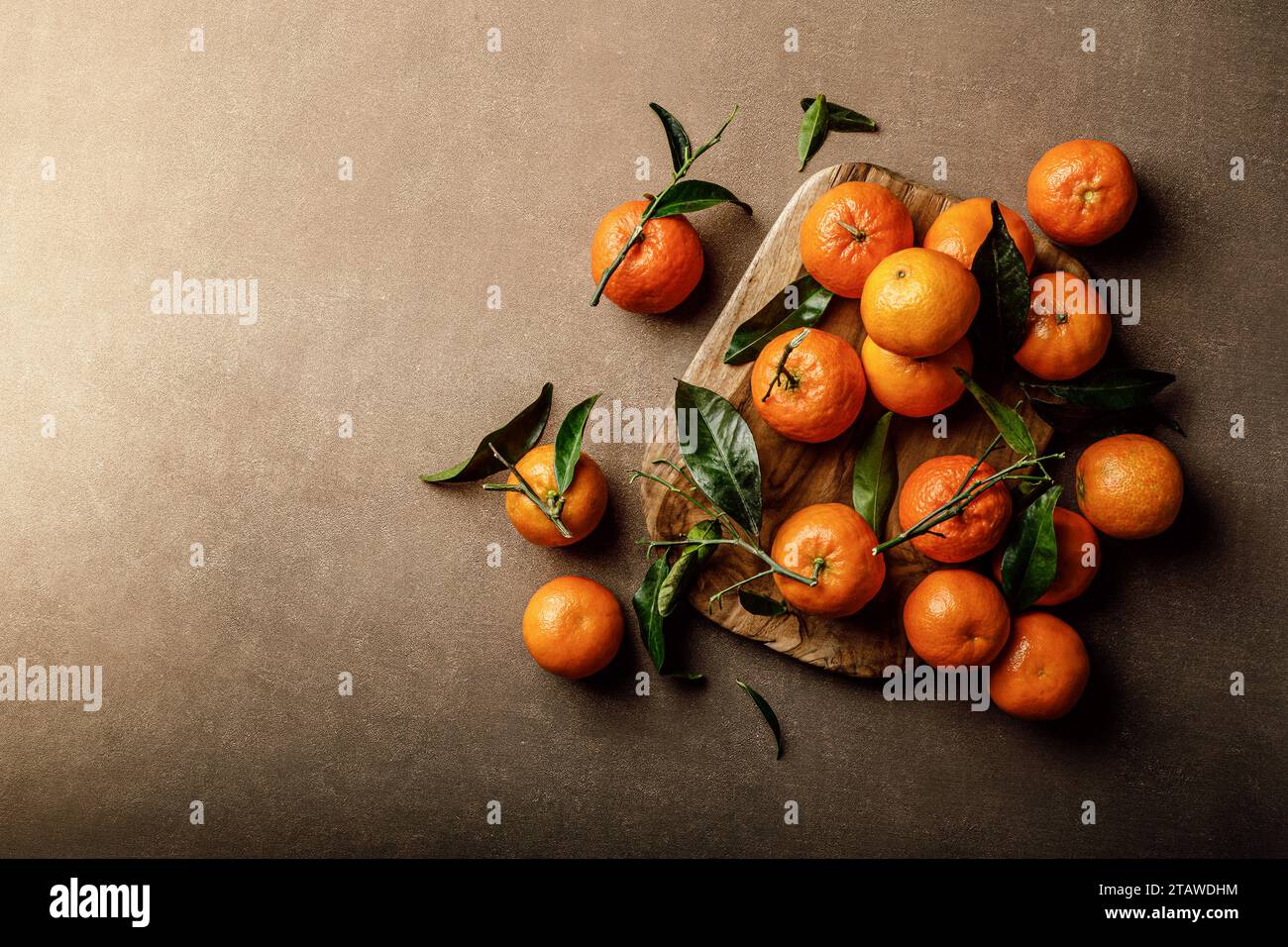Mandarinorangen, Clementinen oder Mandarinen mit Blättern auf dunklem Hintergrund, Draufsicht Stockfoto