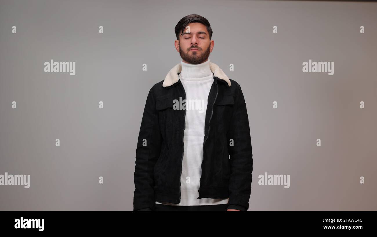 Ein verwirrter junger Mann, der vor grauem Hintergrund denkt. Stockfoto