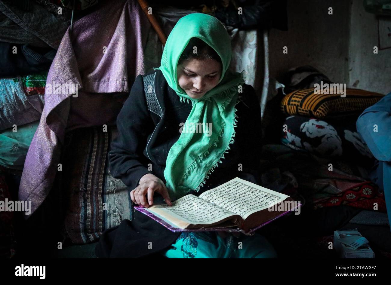 Ein junges muslimisches Mädchen, das den Koran liest, während es Hijab und traditionelle islamische Kleidung trug. Stockfoto