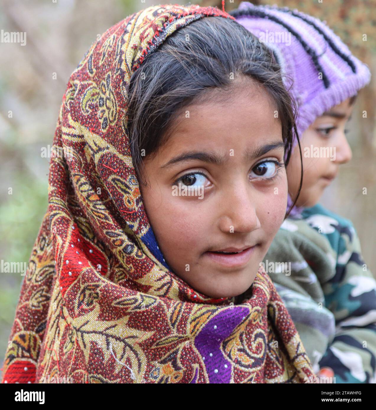 Fröhliches afghanisches Mädchen mit traditionellem Outfit, lächelnd und in die Kamera schauend. Stockfoto
