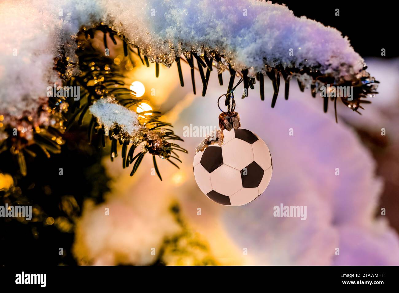 Fußball hängt am Weihnachtsbaum im Schnee, ideal für Fußballvereine, Nahaufnahme, Weihnachtsgrüße Stockfoto