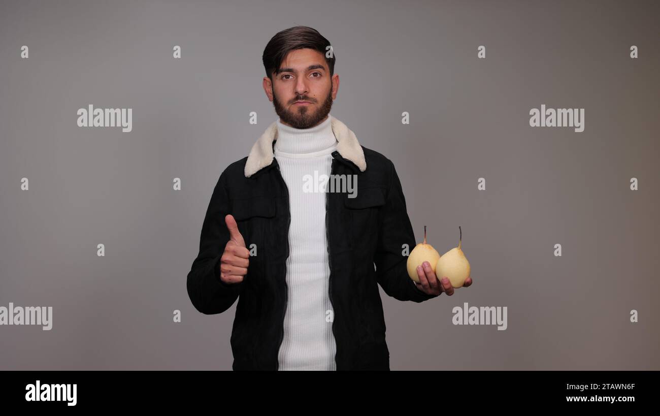 Ein junger Mann, der Birnen hält und die Menschen ermutigt, Birnen zu essen. Stockfoto