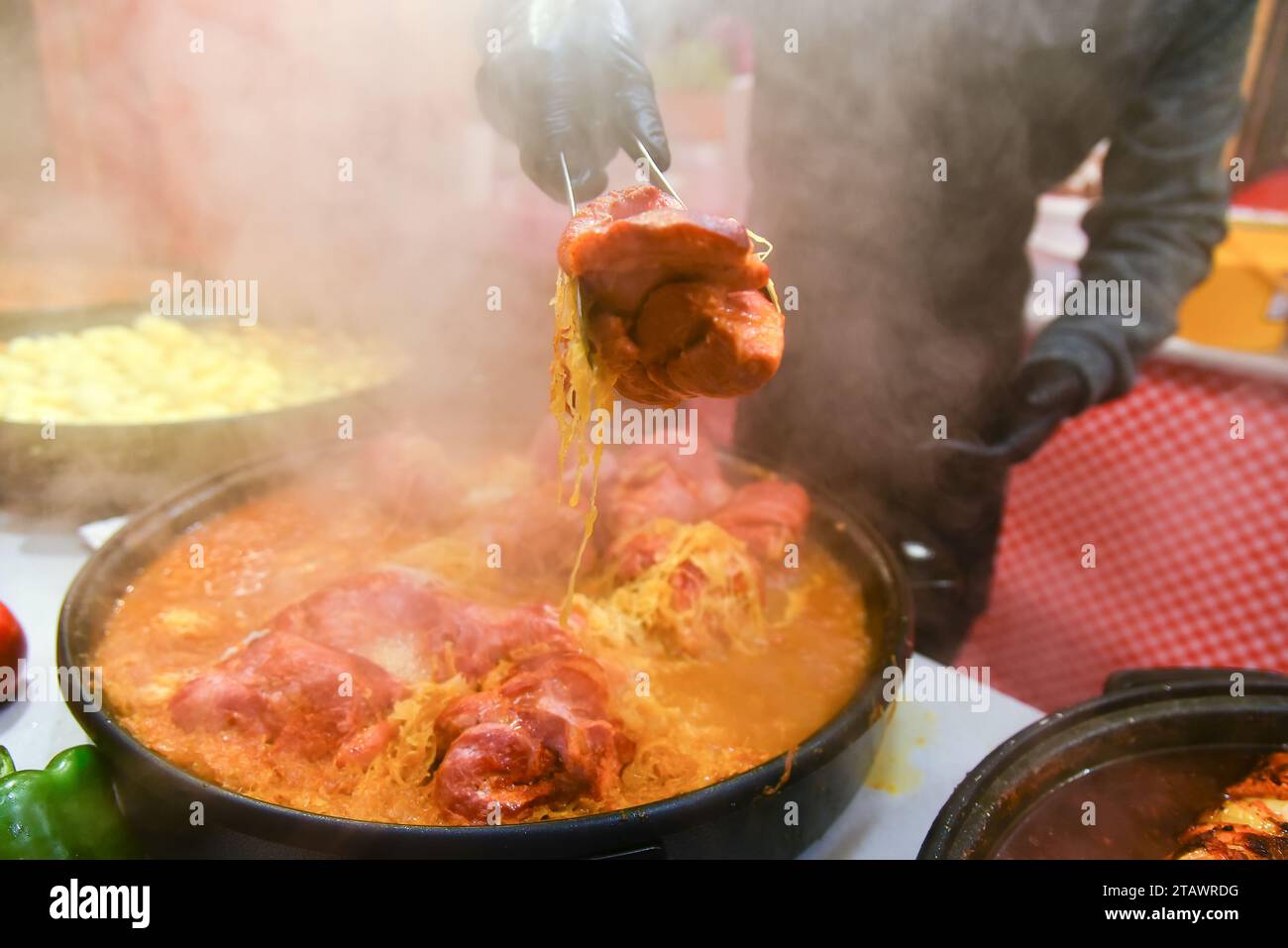 Leckeres Streetfood, Fleisch. Dampfende, warme Speisen, die draußen zubereitet werden. Der Verkäufer zeigt ein Stück frittiertes Fleisch, einen Imbissstand. Stockfoto