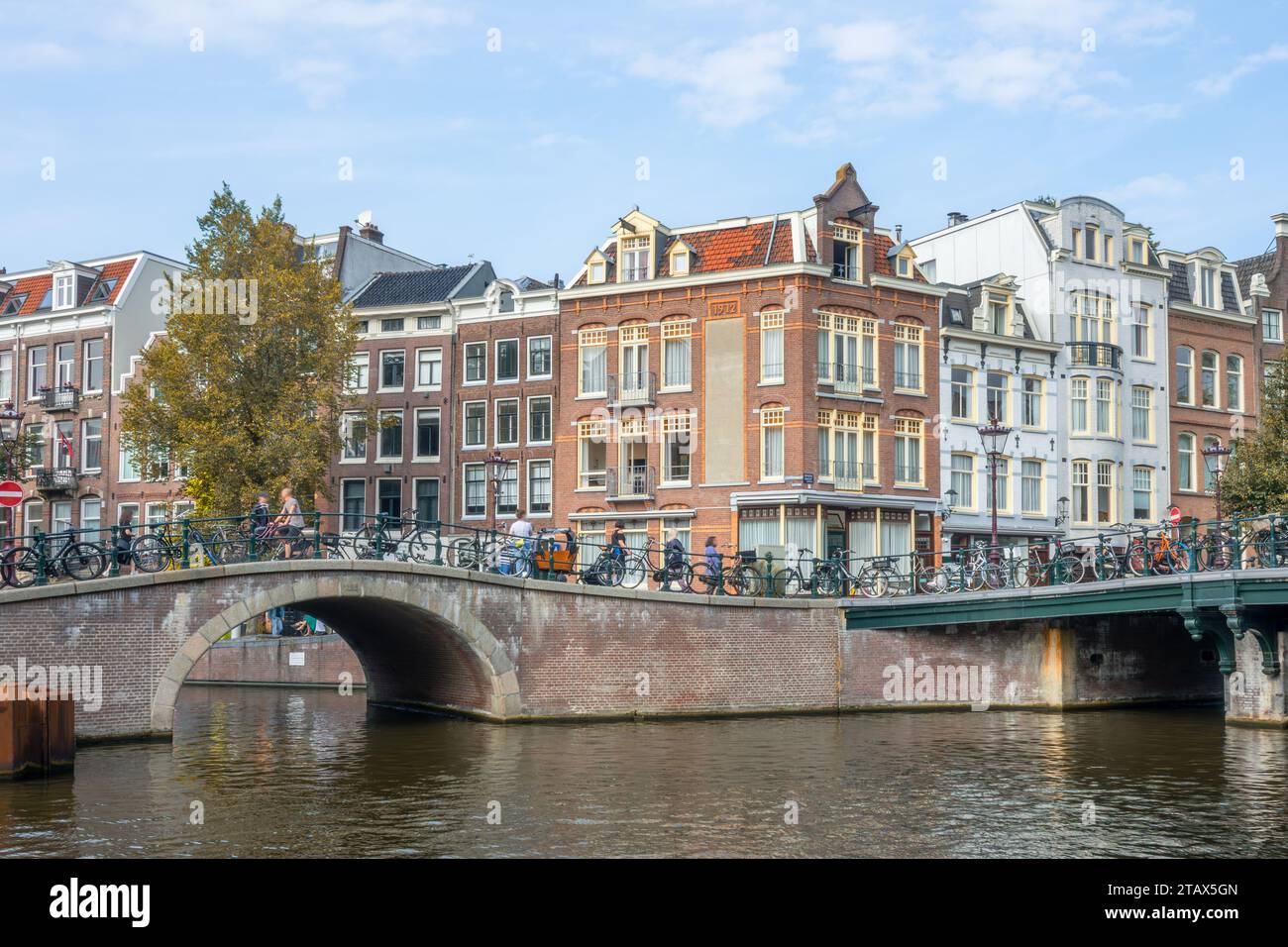 Niederlande. Herbsttag. Typisch holländische Häuser an der Uferpromenade von Amsterdam. Steinbrücken am Zusammenfluss von Kanälen Stockfoto