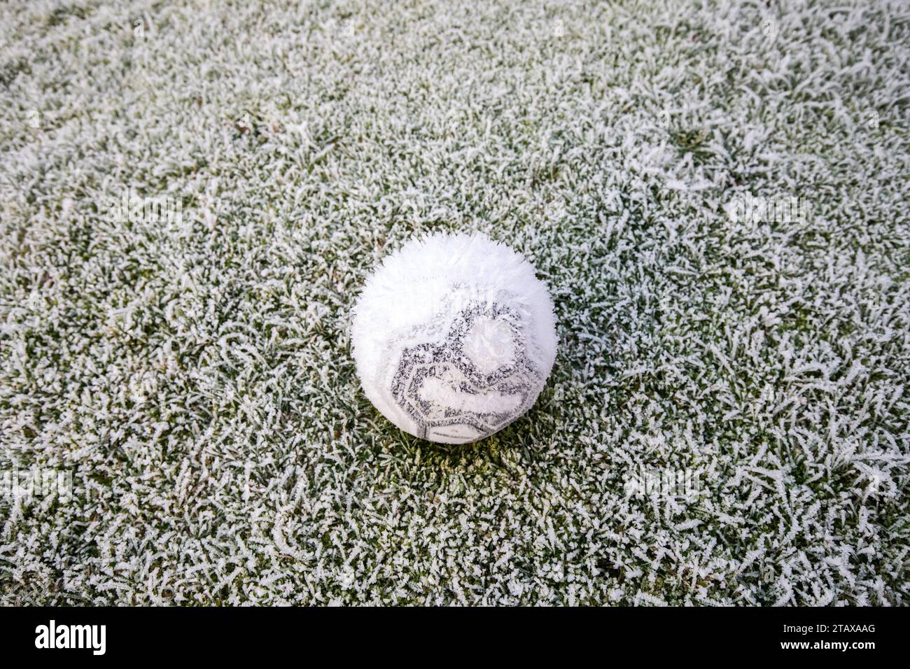 Gefrorener Fußball auf einem gefrorenen Feld, das im Winter von Eis und Frost bedeckt ist. Stockfoto