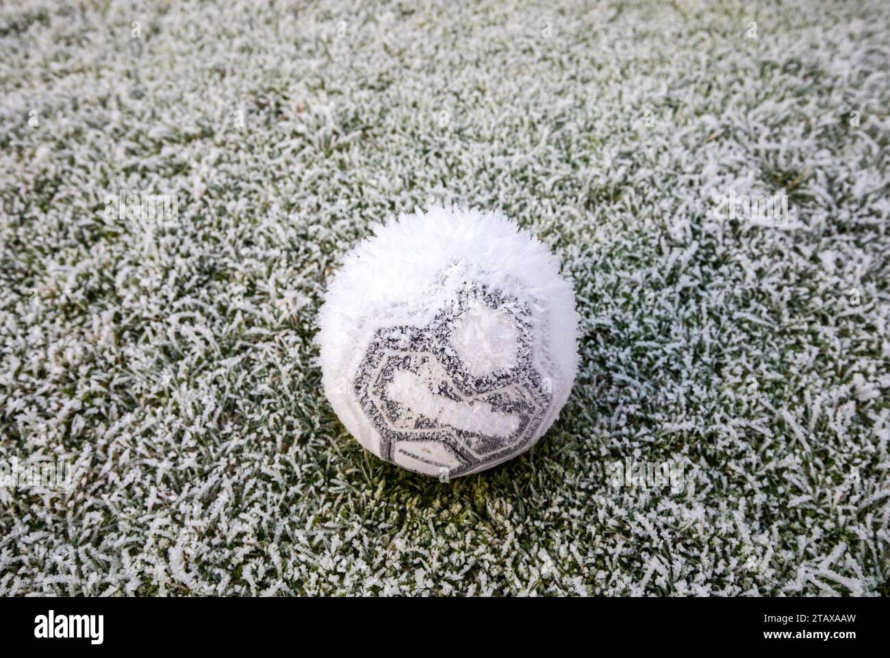 Gefrorener Fußball auf einem gefrorenen Feld, das im Winter von Eis und Frost bedeckt ist. Stockfoto
