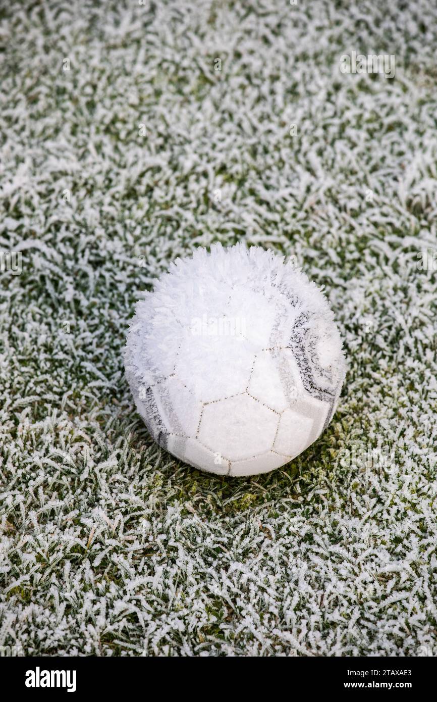 Gefrorener Fußball auf einem gefrorenen Feld, das im Winter von Eis und Frost bedeckt ist. Stockfoto