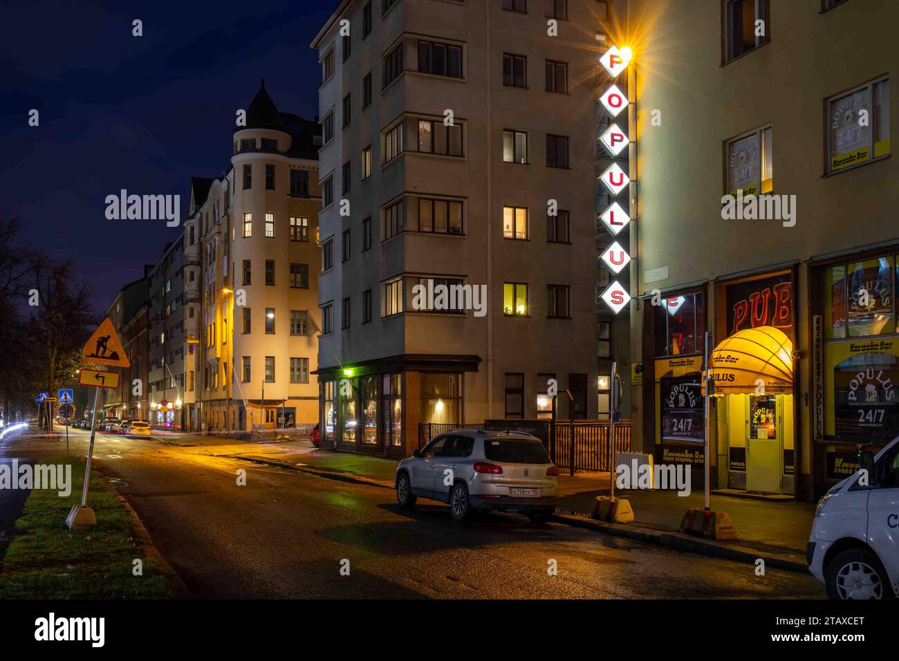 Blick auf die Straße Aleksis Kiven Katu nach Einbruch der Dunkelheit mit Populus Tauchbar-Schrankschild im Bezirk Harju in Helsinki, Finnland Stockfoto