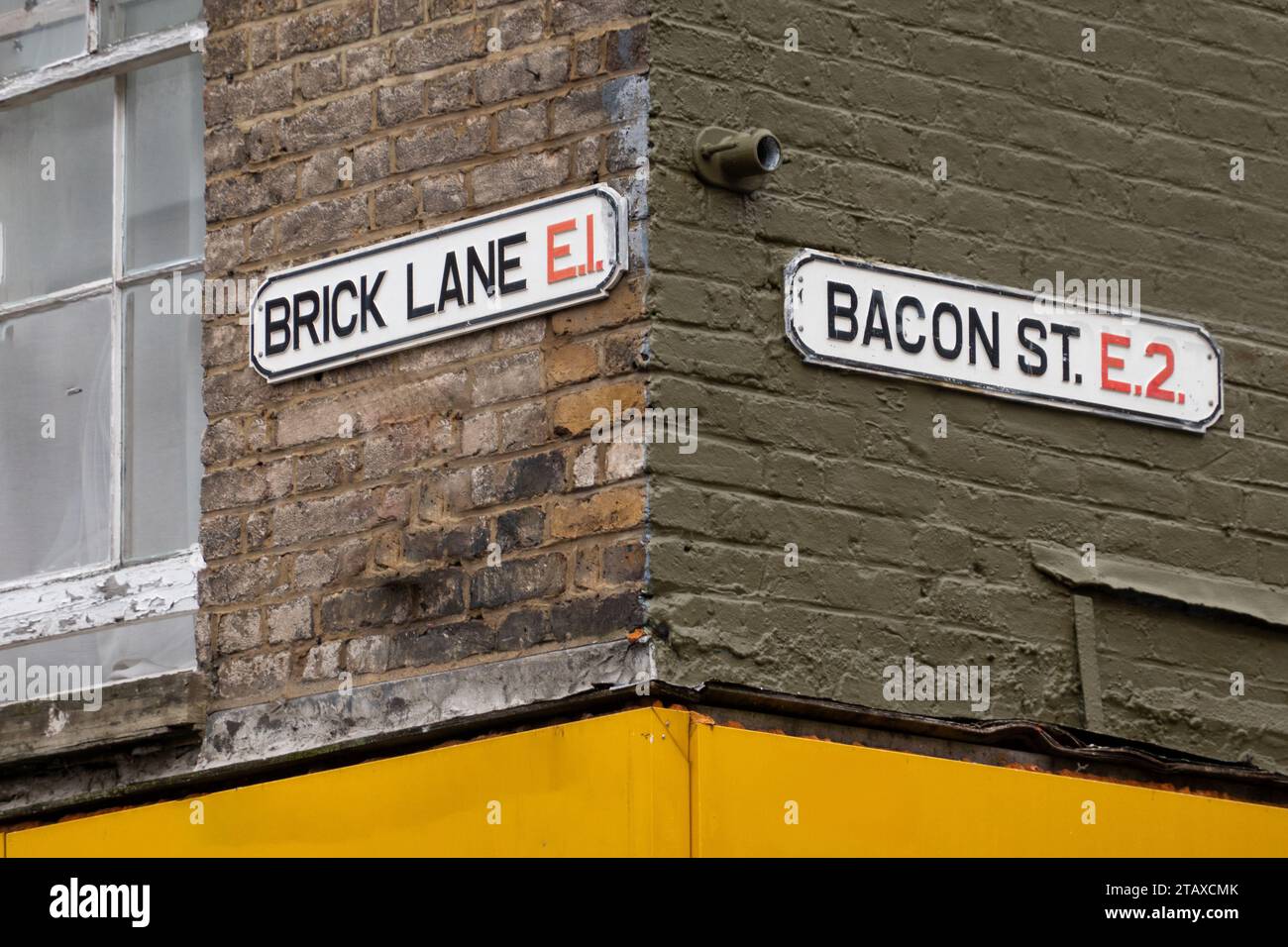 Straßenschilder, an der Gebäudebeschilderung, an der Ecke der Kreuzung von Brick Lane und Bacon St, London, Großbritannien Stockfoto