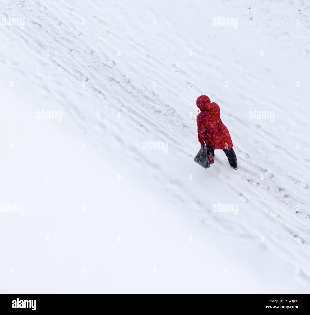 Schuss einer Frau im roten Mantel, die auf dem Schnee läuft Stockfoto