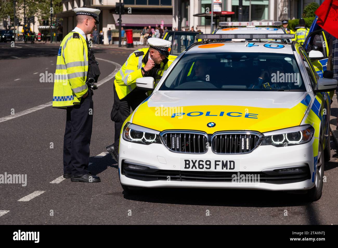 Polizisten der Metropolitan Police, die eine Warnjacke tragen, sprechen mit dem Fahrer eines Streifenwagens, auf der Park Lane im Zentrum von London, Großbritannien. Stockfoto