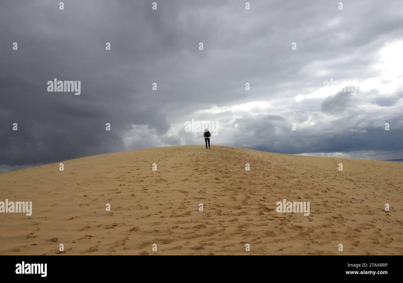 Unter stürmischem Himmel an einem späten Aprilnachmittag steigt ein Wanderer die Dune du Pilat (Landes de Gascogne – Frankreich) Stockfoto