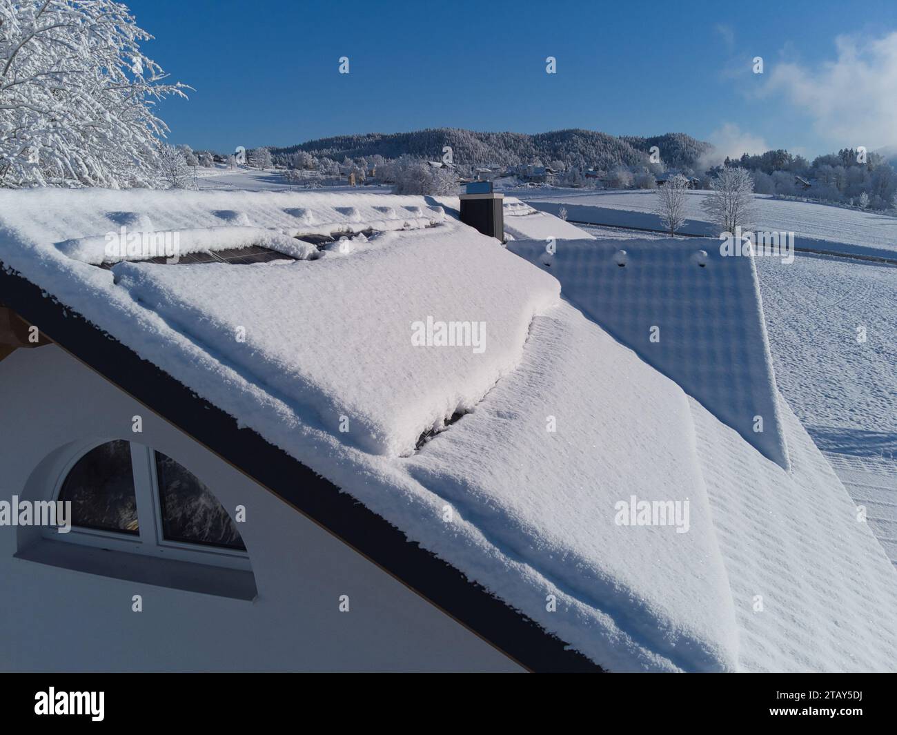 Schneebesen decken Solarpaneele auf einem Hausdach im Winter. Trotz der kühlen Umgebung sind die Photovoltaik-Panels widerstandsfähig. Perfekt für Illustratoren Stockfoto