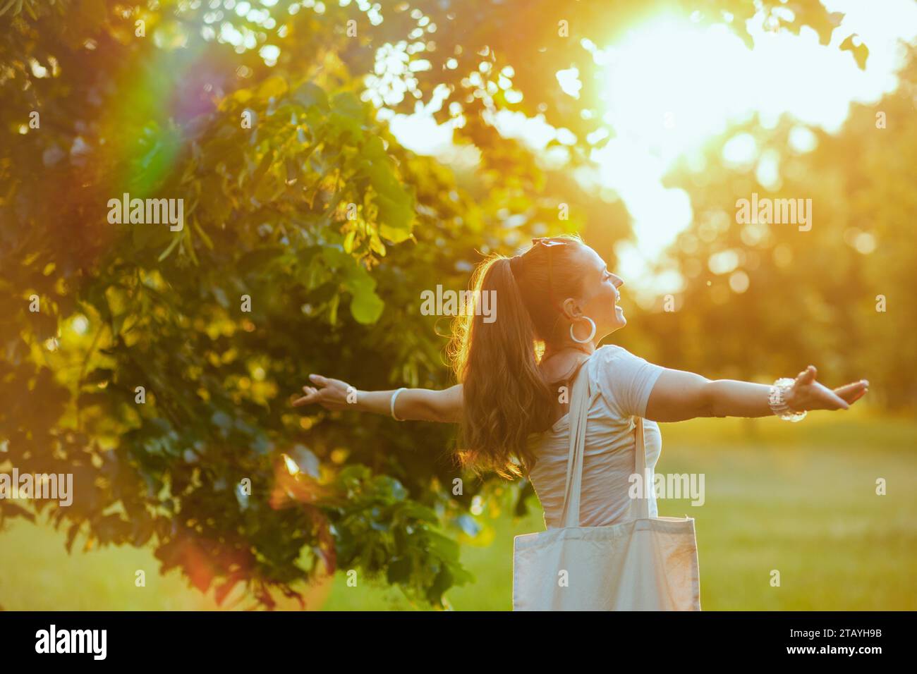 Sommerzeit. Glückliche, stilvolle 40-jährige Frau in weißem Hemd draußen. Stockfoto