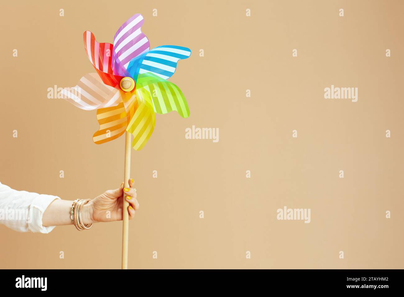 Strandurlaub. Nahaufnahme einer Frau auf Beige mit Windmühlenspielzeug. Stockfoto Strandurlaub. Nahaufnahme einer Frau auf Beige mit Windmühlenspielzeug. Stockfoto