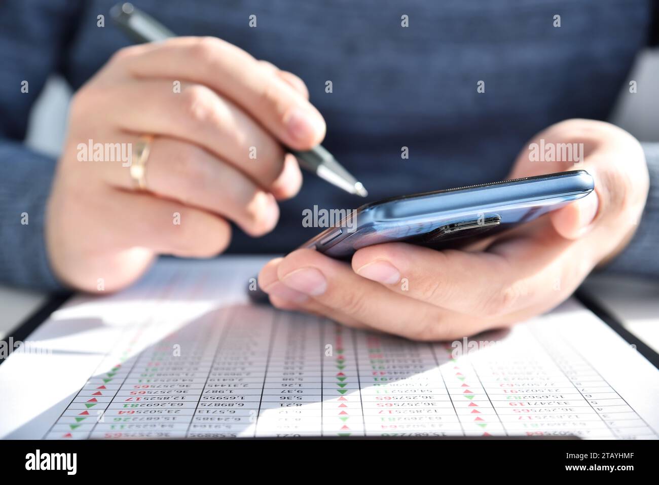 Händlermann mit Stift in der Hand mit Smartphone und Aktienstatistik auf dem Bildschirm. Internet-Handel und Geschäftskonzept. Nahaufnahme Stockfoto