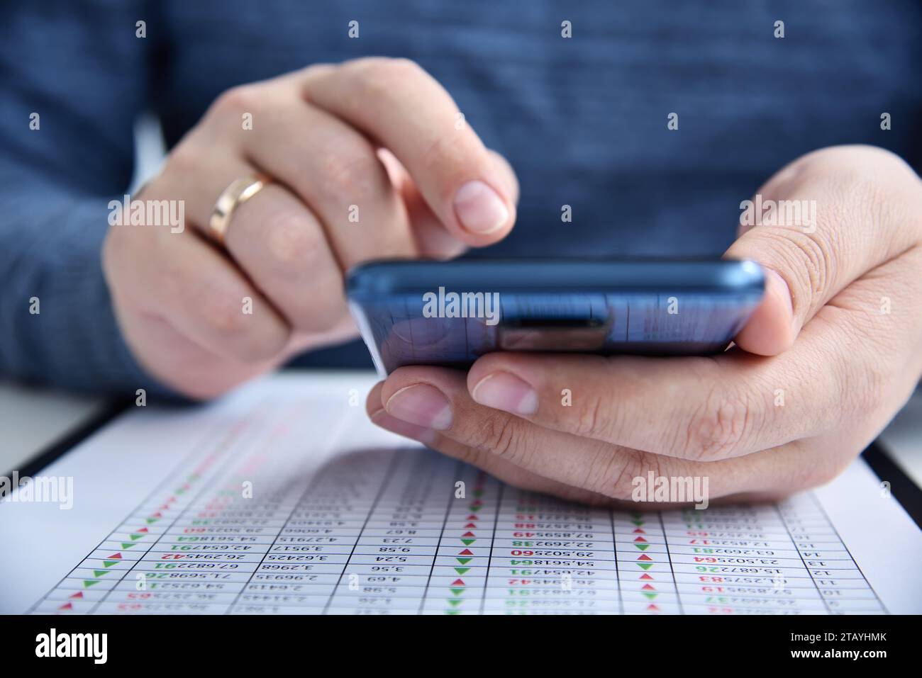Geschäftsmann hält Smartphone und Finanzdaten auf dem Tisch. Geschäfts- und Finanzkonzept. Nahaufnahme Stockfoto