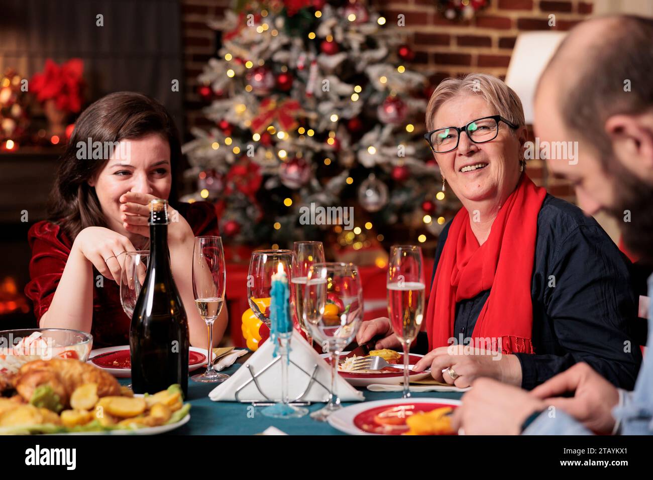 Oma feiert weihnachten mit der Familie beim traditionellen Winteressen mit ihren Lieben und genießt den Urlaub am Tisch zu Hause. Senior Person trifft sich mit Verwandten und Freunden auf Weihnachtsfeier. Stockfoto