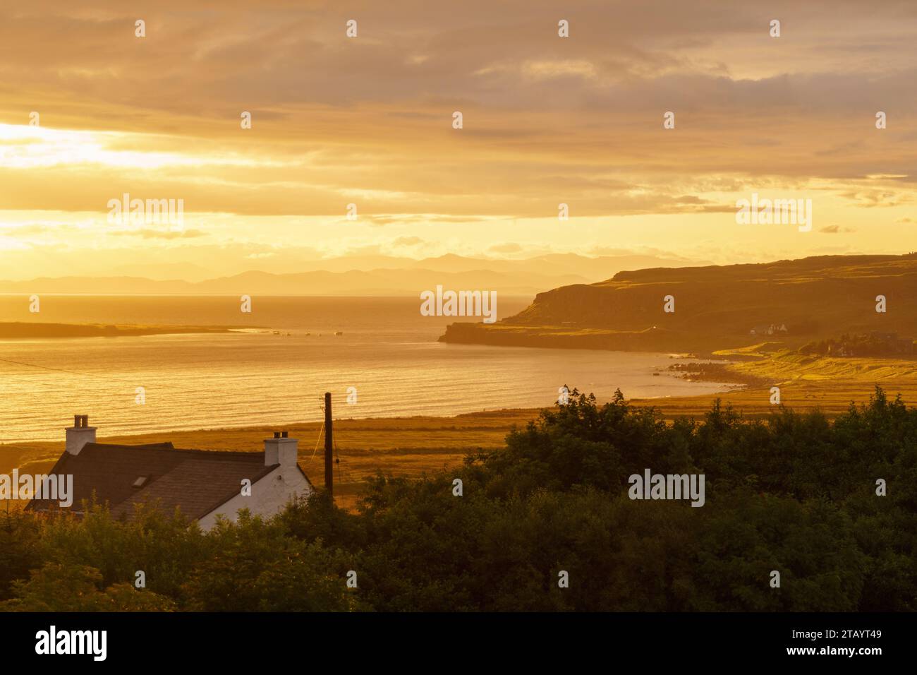 Sonnenaufgang auf der Isle of Skye über einem Baum und Dach, mit sichtbaren Küstenelementen Stockfoto