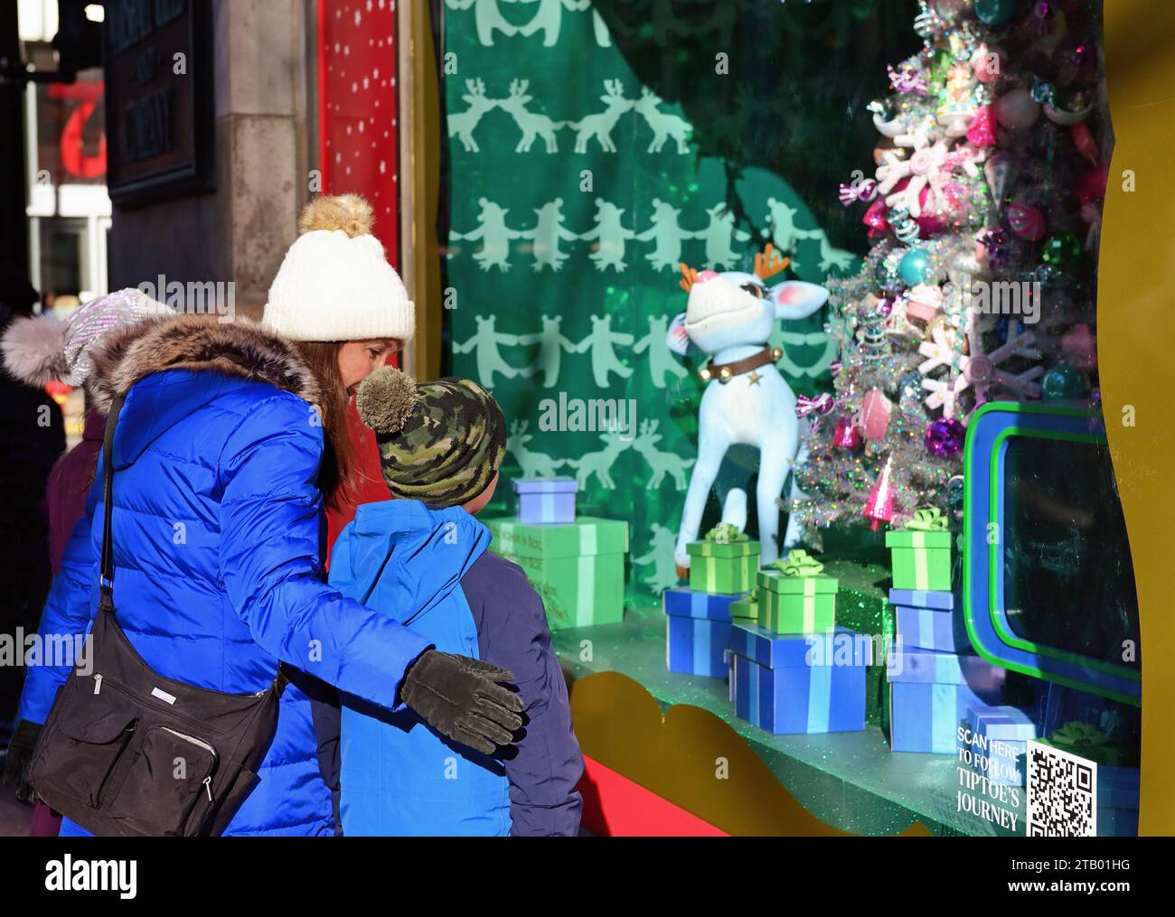 Chicago, Illinois, USA. Kinder und ihre Mutter blicken auf ein weihnachtlich geschmücktes Fenster im Macy's an der State Street. Stockfoto