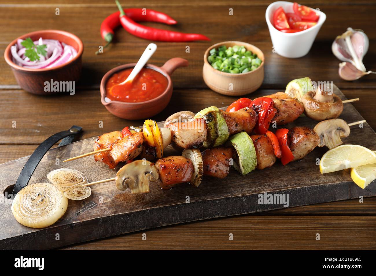 Köstliche Shish Kebabs mit Gemüse auf Holztisch serviert, Nahaufnahme Stockfoto