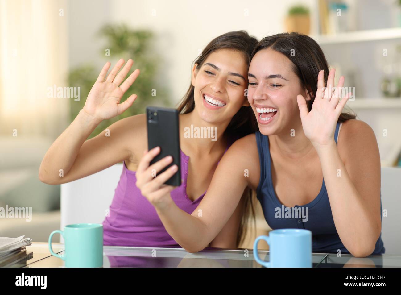 Zwei glückliche Mitbewohner, die zu Hause Videoaufnahmen am Telefon haben Stockfoto