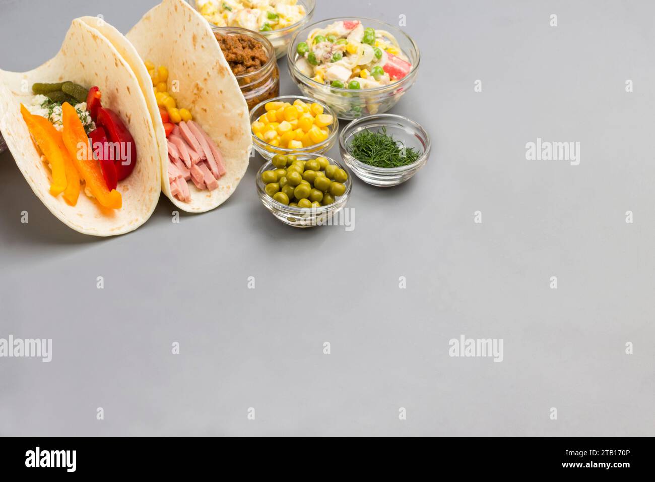 Vegane Tortilla Wraps mit Salat und verschiedenen Gemüsesorten. Gemüsefüllung für Tortilla in Glasschalen. Grauer Hintergrund. Draufsicht. Kopierbereich Stockfoto