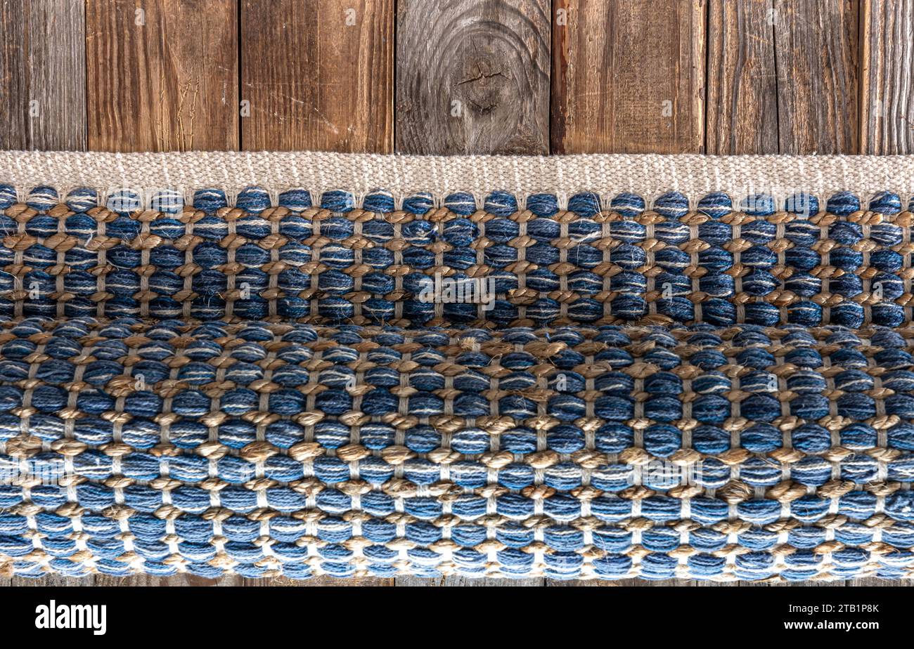 Handgewebter Teppich mit geometrischem Denim-Bereich auf Holzboden. Stockfoto