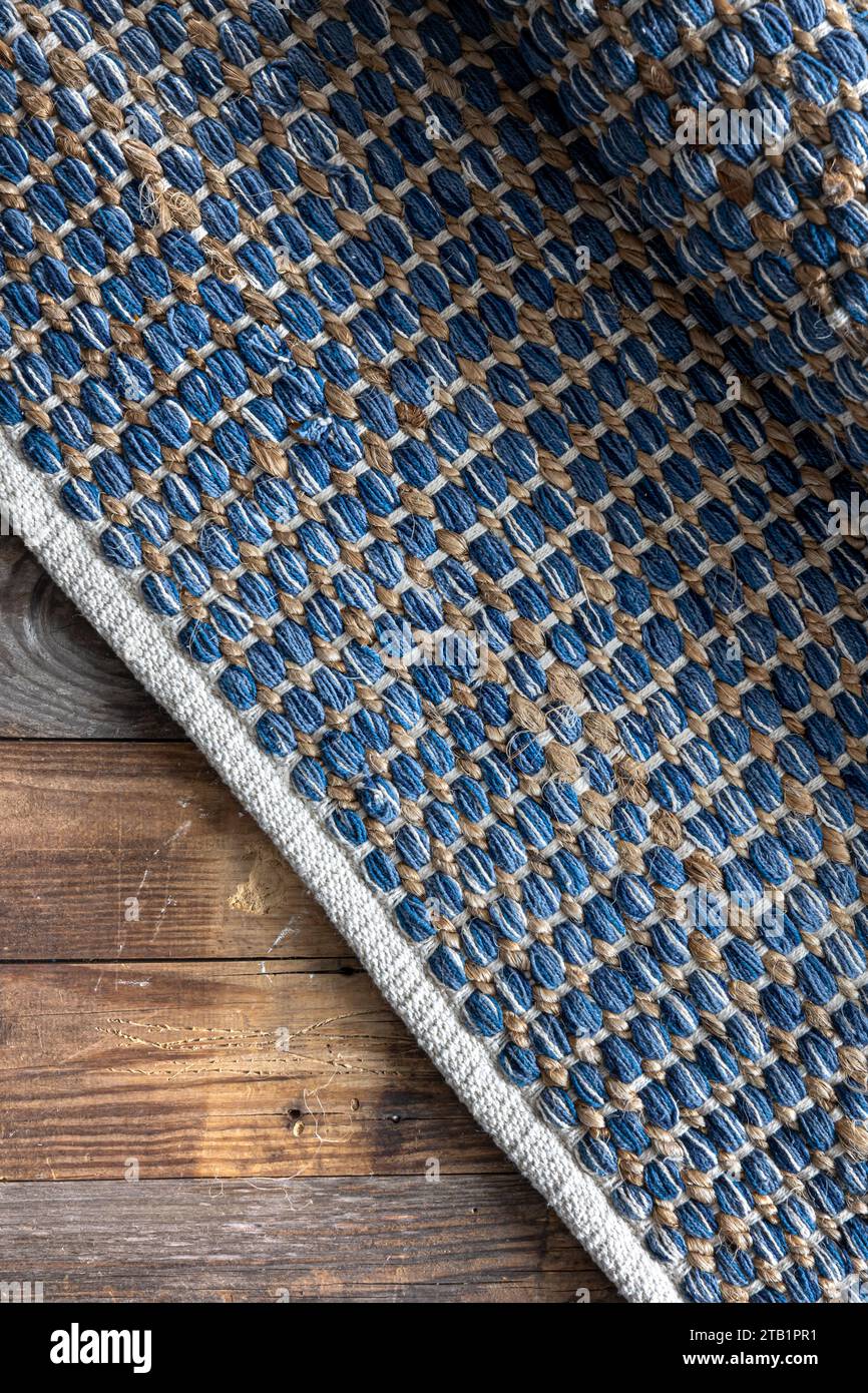 Handgewebter Teppich mit geometrischem Denim-Bereich auf Holzboden. Stockfoto