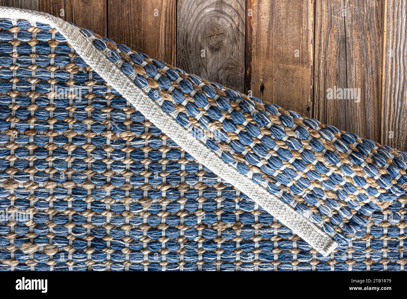 Handgewebter Teppich mit geometrischem Denim-Bereich auf Holzboden. Stockfoto