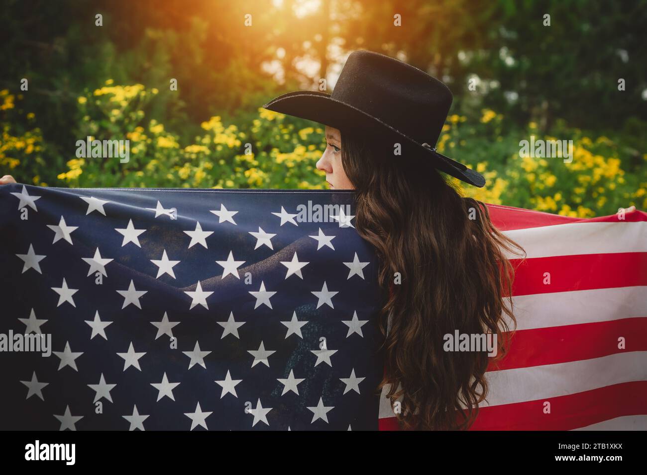 Junger Teenager mit Cowboyhut, der die amerikanische Flagge hält Stockfoto