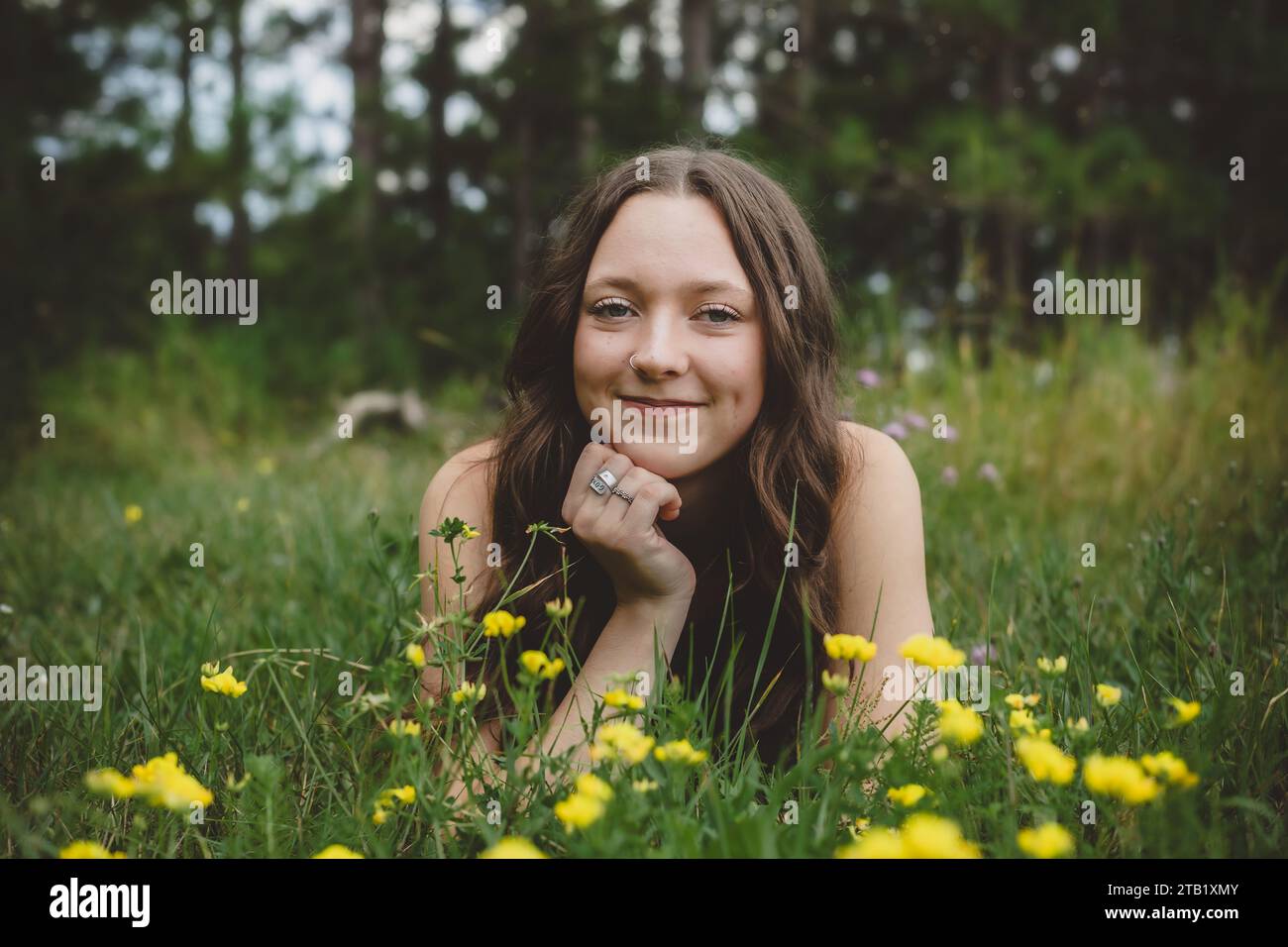 Junges lächelndes Teenager-Mädchen, das im Blumenfeld liegt Stockfoto
