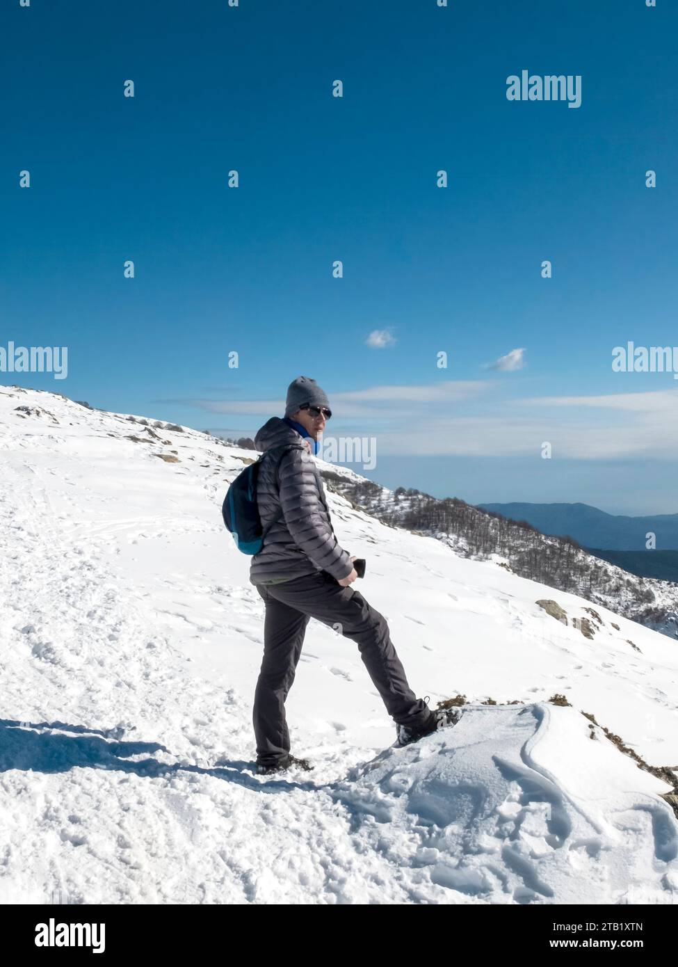 Mann in einer Wollmütze mit Kamera auf einem verschneiten Berg Stockfoto