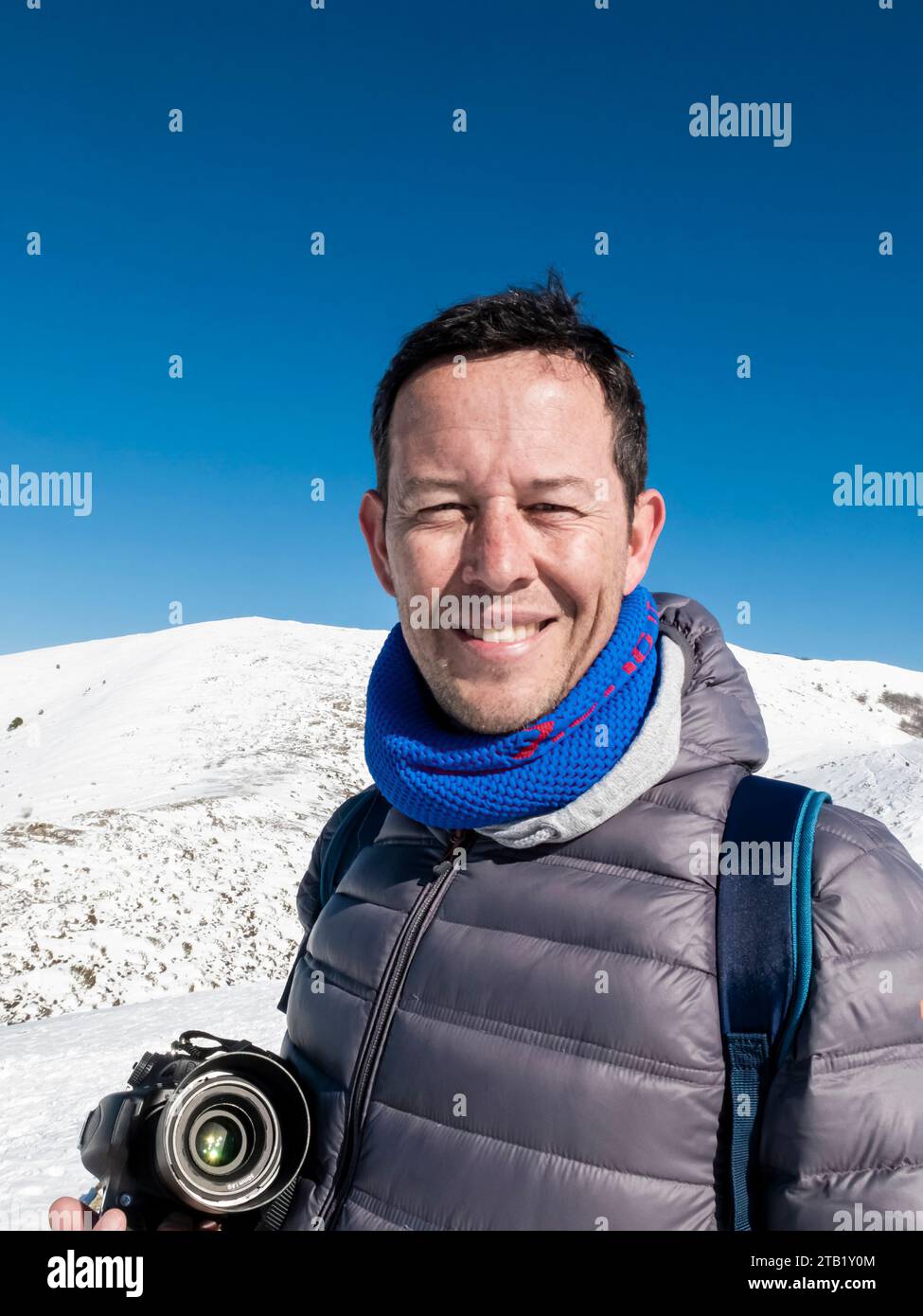 Mann in einer Wollmütze mit Kamera auf einem verschneiten Berg Stockfoto