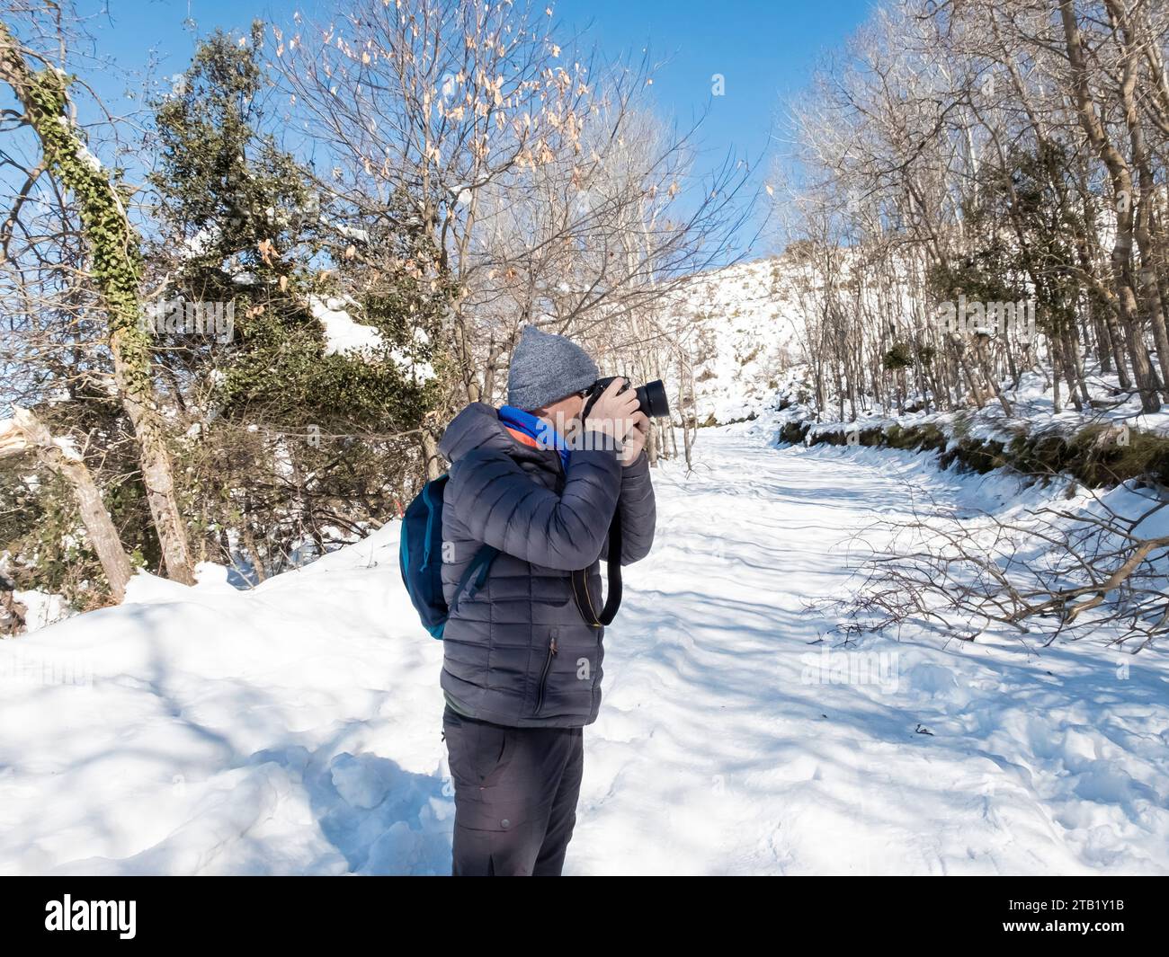 Mann in einer Wollmütze, der Fotos auf einem schneebedeckten Berg macht Stockfoto