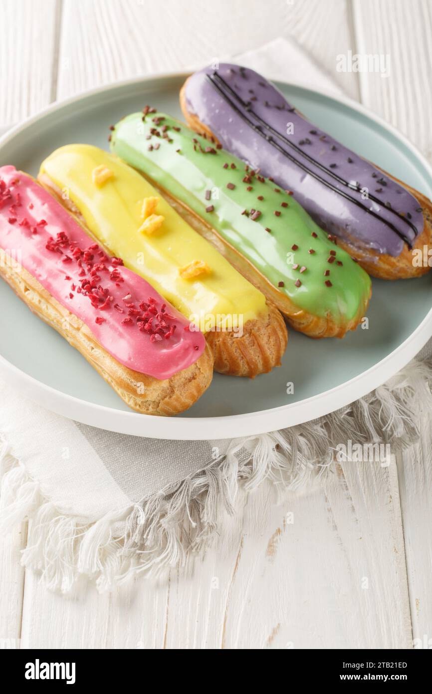 Gruppe französischer Dessert Eclair Nahaufnahme auf Teller auf hölzernem Hintergrund. Vertikal Stockfoto