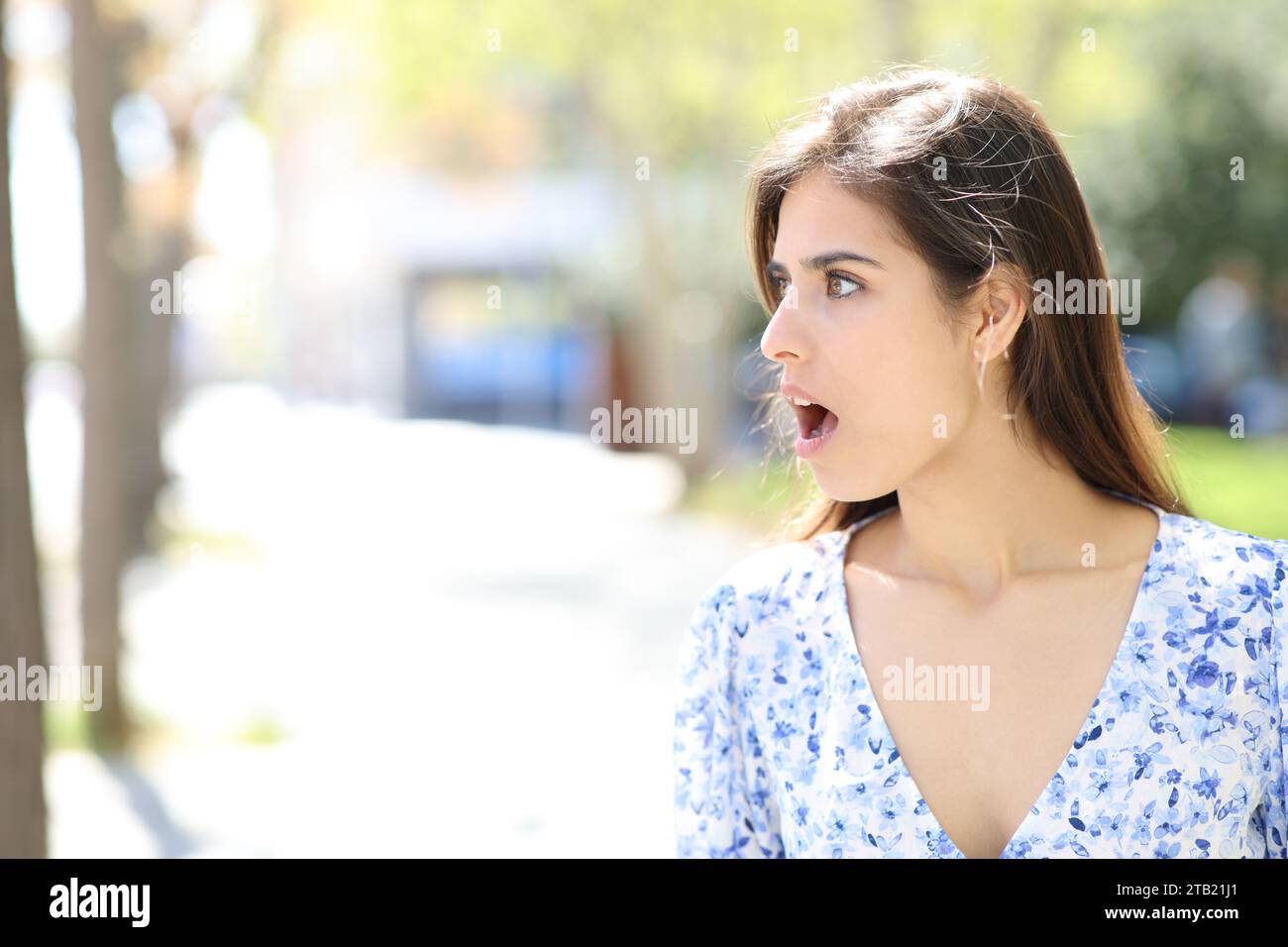 Überraschte Frau, die auf die Seite blickt, die auf der Straße steht Stockfoto