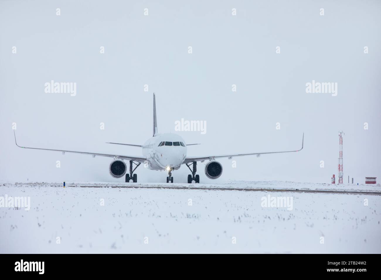 Verkehr am Flughafen bei Schneefall. Passagierflugzeug, das an frostigem Wintertag zum Start auf die Start- und Landebahn fährt. Stockfoto